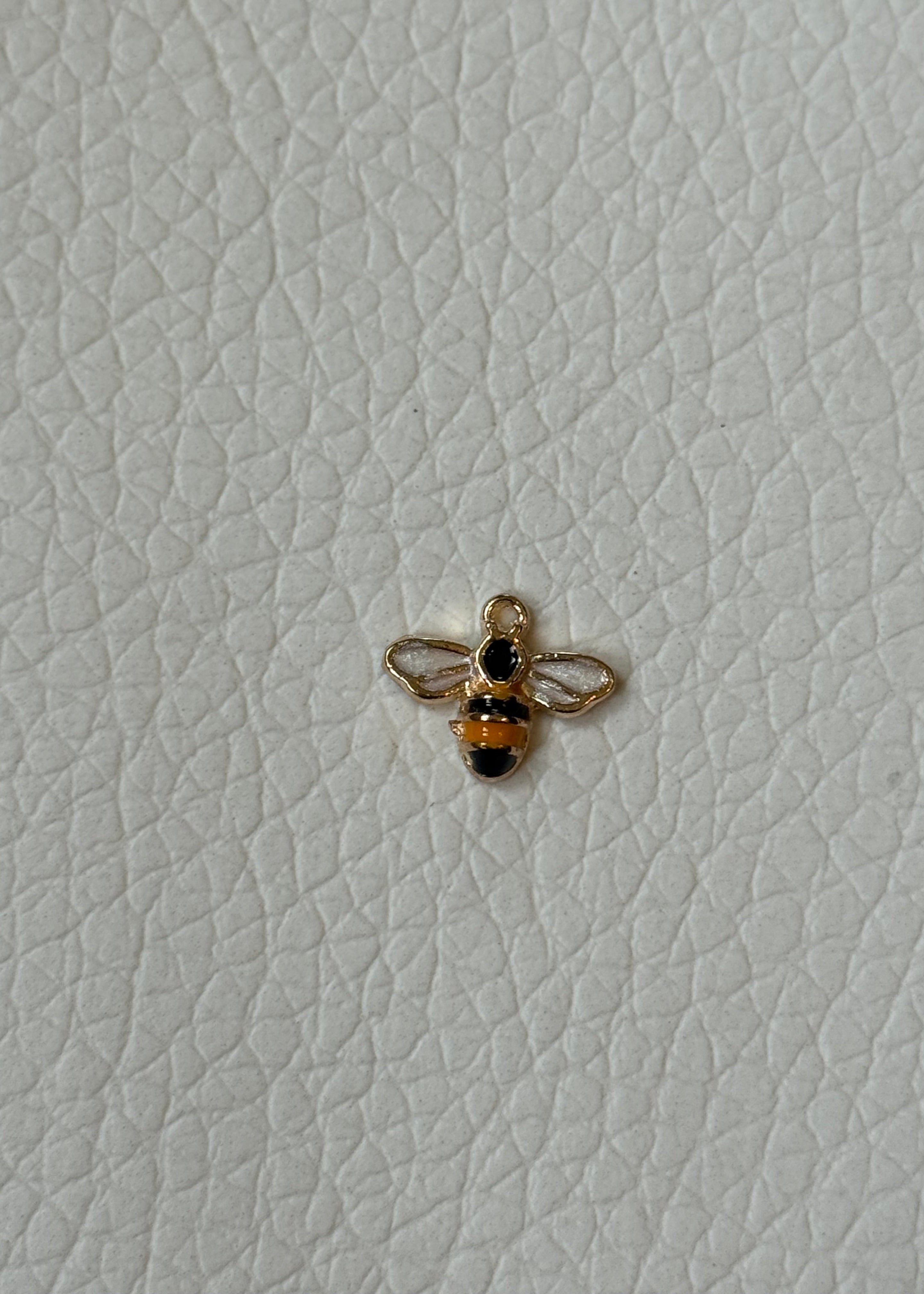 Gold honeybee charm with white enamel wings on white background