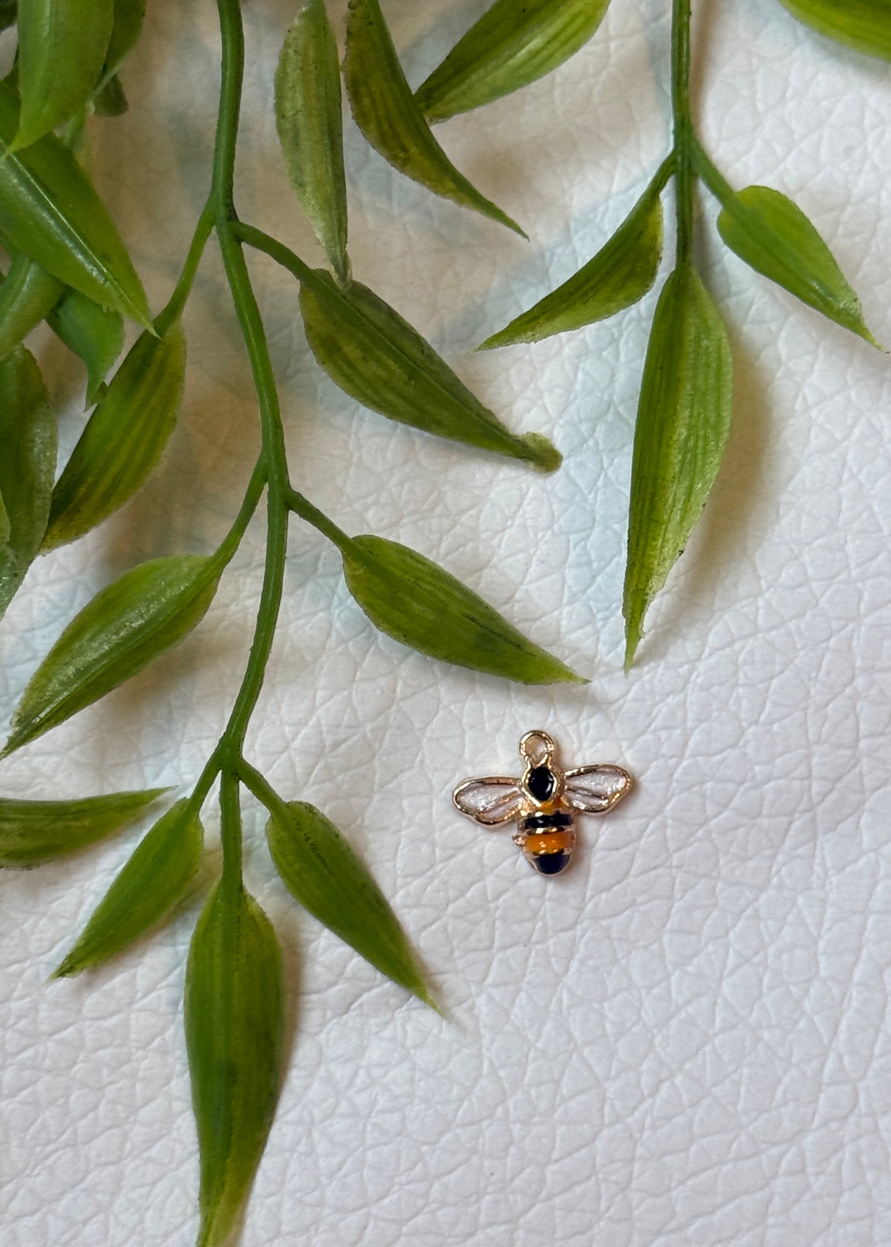 Gold honeybee charm with white enamel wings styled with greenery