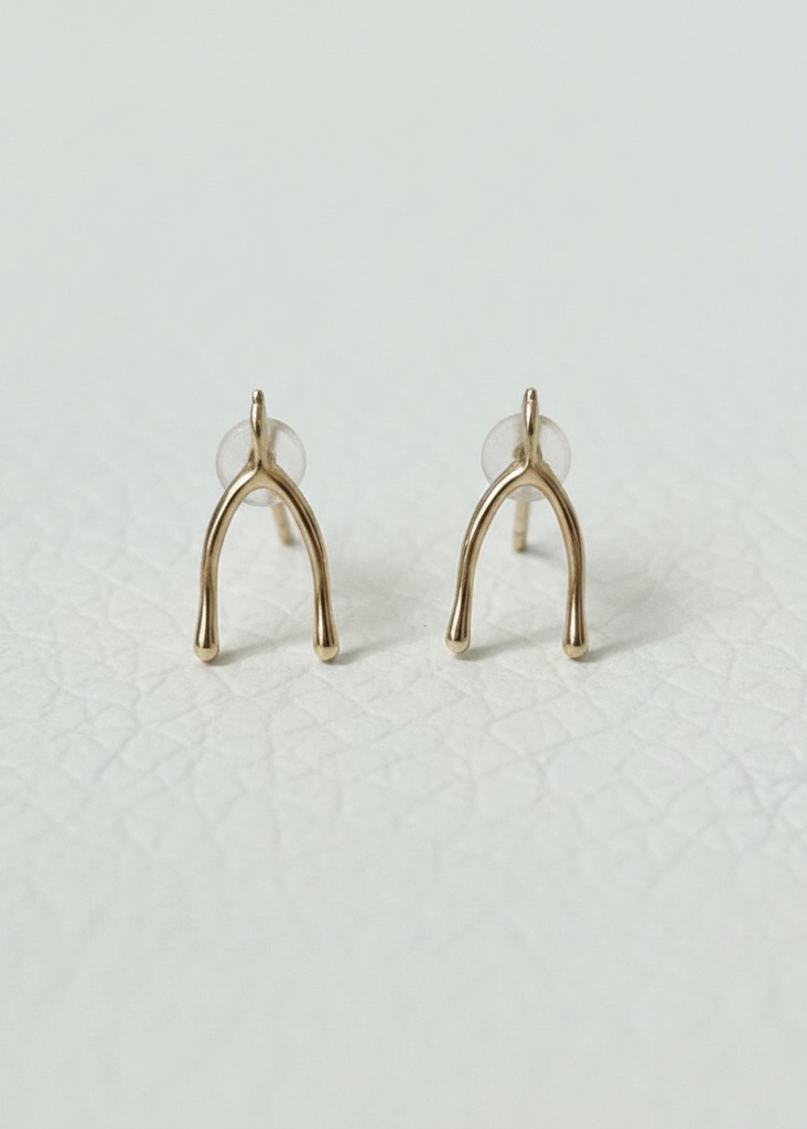 Close-up of vintage 9K gold wishbone stud earrings on white background